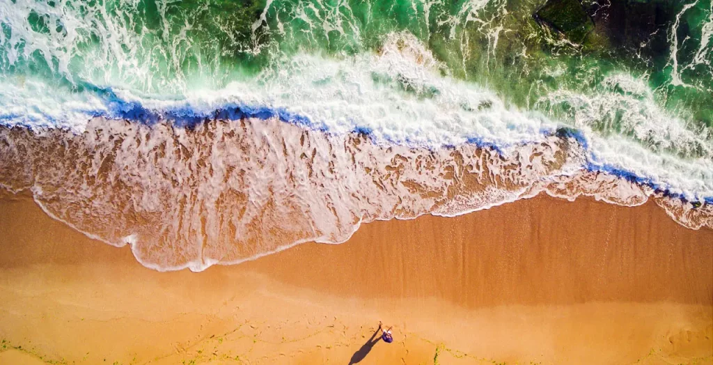 Luftaufnahme einer Person am Goldstrand in Bulgarien mit Wellen, die auf den Sand treffen