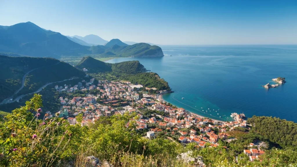 Panoramablick auf Petrovac in Montenegro, umgeben von grünen Hügeln und klarem blauen Wasser der Adria