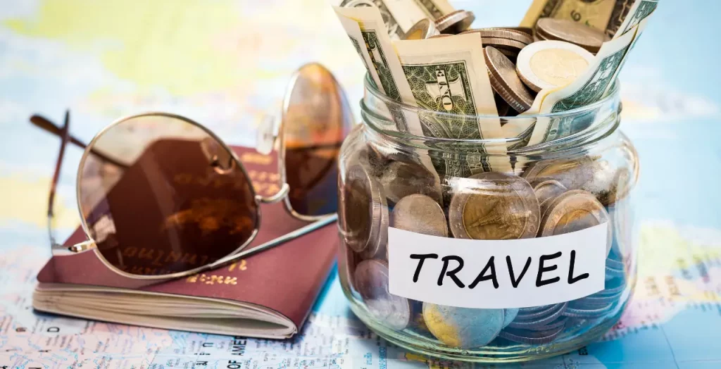 Sparglas mit Geld für Reisen, Pass und Sonnenbrille auf einer Landkarte [Bildquelle: © surasaki | Canva]