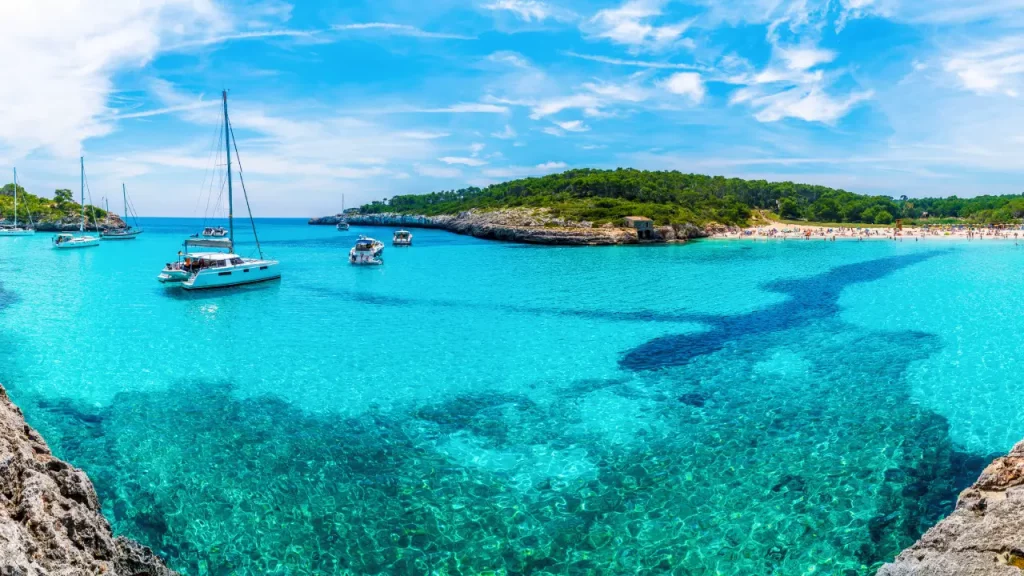 Segelboote auf dem klaren türkisfarbenen Wasser der Cala Mondrago Mallorca, umgeben von üppiger Natur