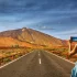 Frau fotografiert eine Straße mit Blick auf den Teide, Teneriffa, Spanien. Vulkanlandschaft und blauer Himmel. [Bildquelle: © csh3d | Canva]